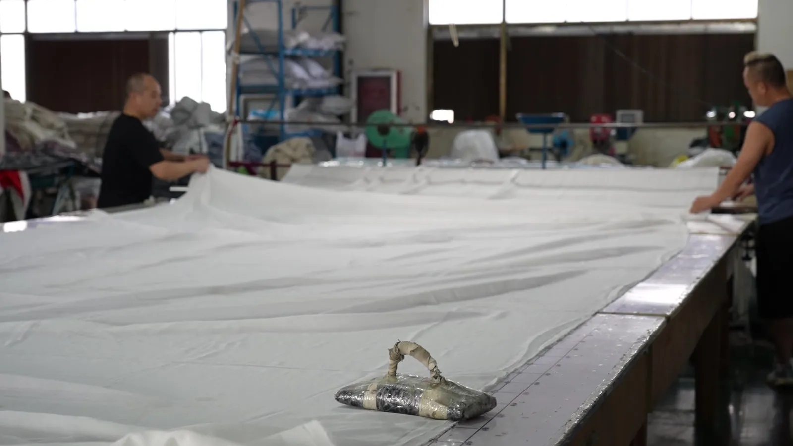 Curtain fabric laid out on a long cutting table at Xinlan